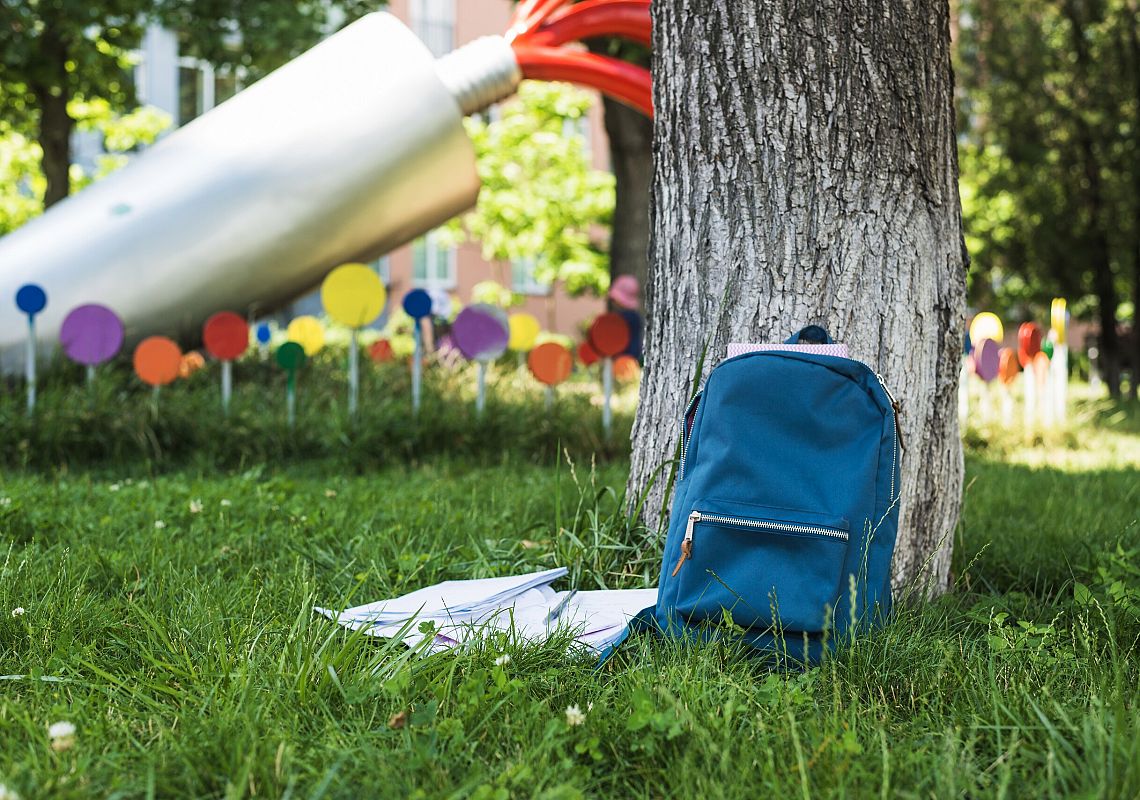 Źródło grafiki: Obraz autorstwa <a href="https://pl.freepik.com/darmowe-zdjecie/trawnik-w-parku-z-plecakiem-dla-studentow_1314160.htm#query=holiday%20school&position=3&from_view=search&track=ais">Freepik</a>